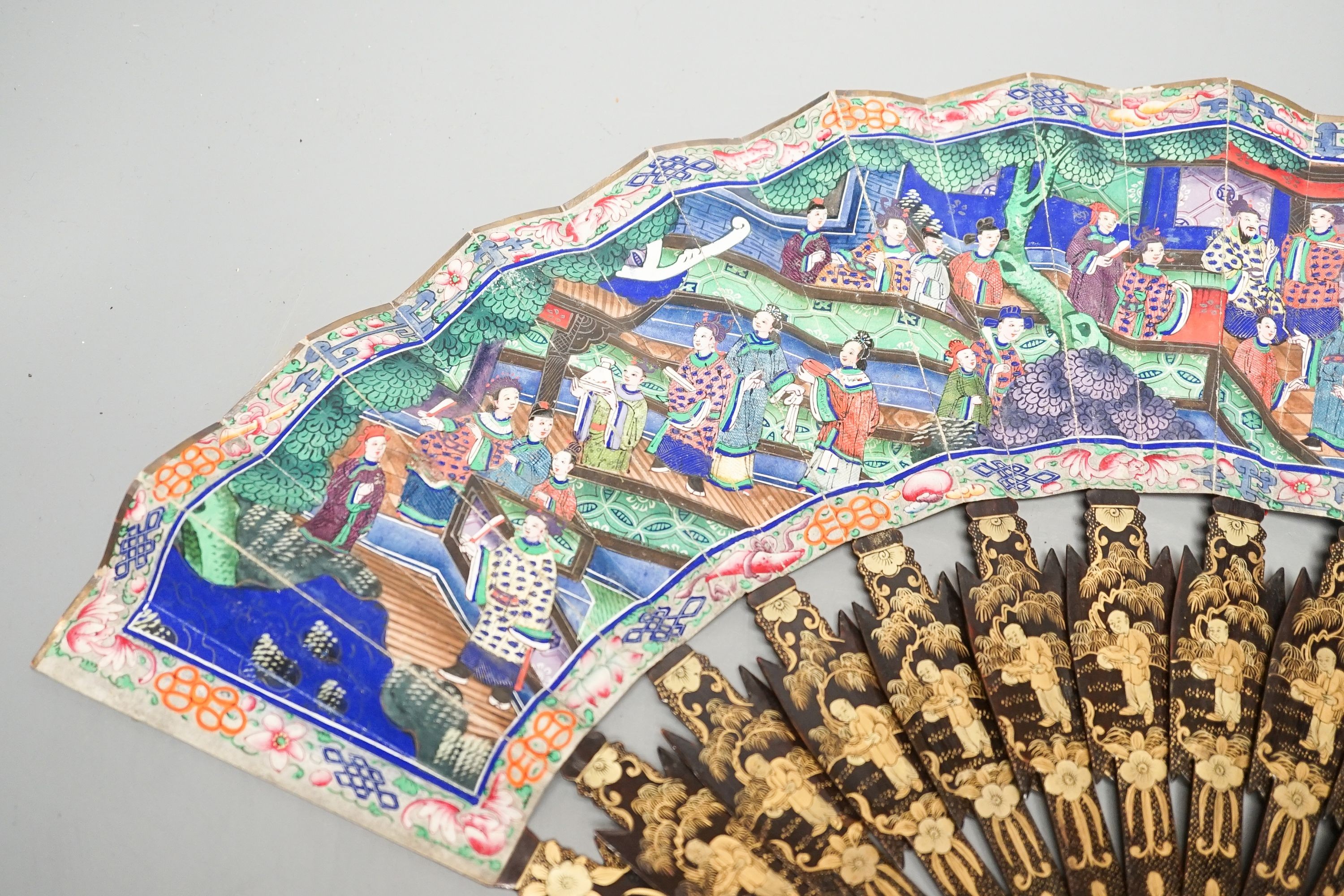 A Chinese export gilt decorated lacquer fan and box, mid 19th century, the appliqué work paper fan leaf decorated with figures amid pavilions and trees, box 32cm